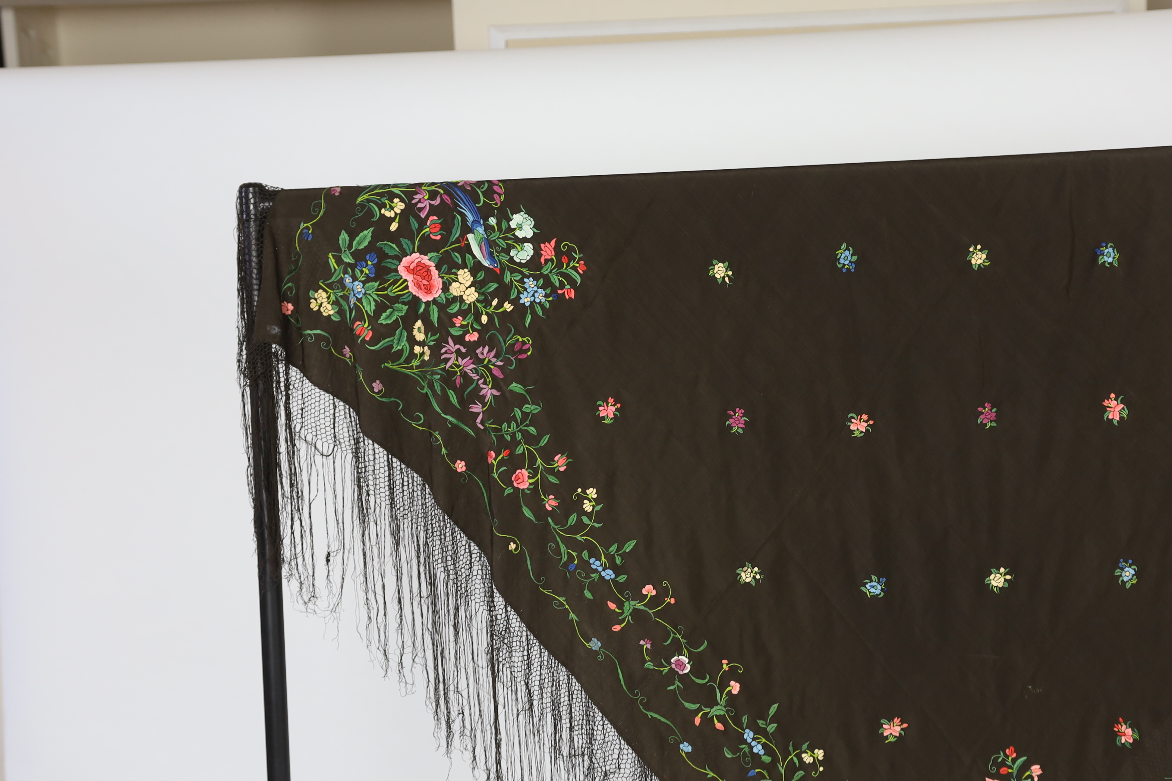 A Chinese silk shawl, circa 1900, embroidered with polychrome threads with birds and flowers against a black silk ground, 164cm sq.